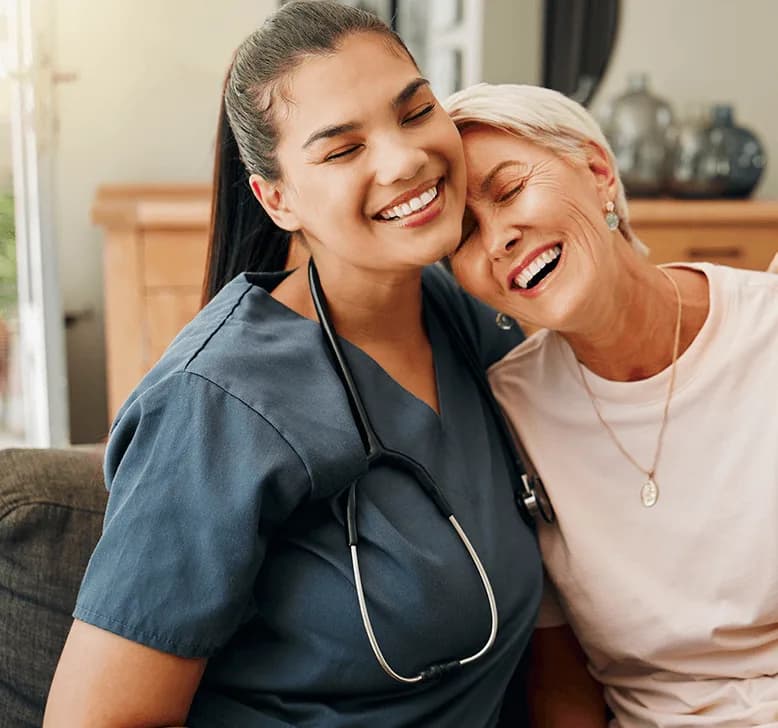 A smiling nurse in scrubs sharing a warm moment with an older patient
