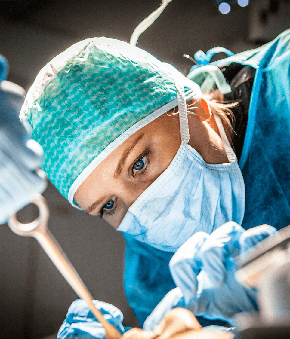 A surgical nurse in cap and mask at work in the operating room